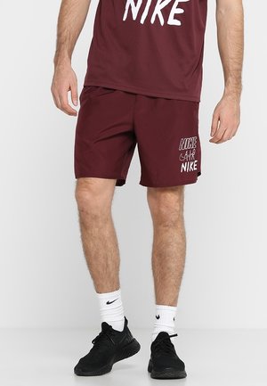 Burgundy athletic shorts with an elastic waistband, featuring a white Nike logo on the left thigh and a lightweight, smooth fabric.