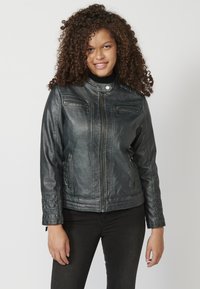 Giacca da moto in pelle nera con zip frontale, due tasche sul petto e tasche laterali. Presenta un colletto a pressione e dettagli trapuntati sulle maniche.