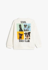 Sweatshirt blanc avec un motif au dos comprenant quatre images de chiens, le texte en gras "COOL DOGS CLUB" et des carrés en arrière-plan de couleurs contrastées.