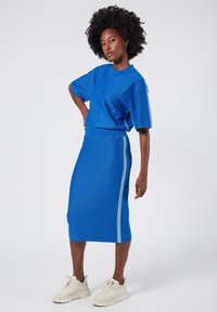 Blue sparkly knit top and midi skirt set with a side stripe detail, paired with cream sneakers. Smooth texture and fitted design.