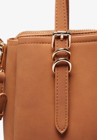 Borse in ecopelle marrone con accessori in metallo dorato, caratterizzata da una texture liscia, doppi accenti ad anello e chiusura con zip nella parte superiore.