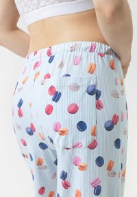 Lichtblauwe pyjamabroek met verticale strepen, met een macaroonprint in verschillende kleuren. Elastische tailleband en zijzakdetail.