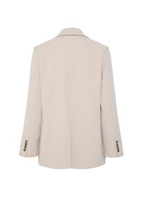 Beige bleiseri, joka on muotoiltu kauluksella, pitkillä hihoilla ja nappikiinnityksillä. Sujuva kangas, jossa on jämäkkä siluetti ja minimaalinen yksityiskohtaisuus.