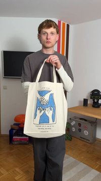 Sac fourre-tout en toile avec un design en bleu et blanc dessiné à la main. Poignées solides, couleur crème, et texte en bas. Forme simple et fonctionnelle.