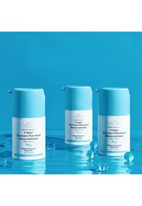 Three cylindrical, pastel blue skincare containers with white labels. Features a flip-top lid and contains hydrating facial masque.