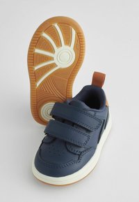 Baskets pour enfants bleu marine avec deux bandes Velcro réglables, semelle intermédiaire blanche, semelle en caoutchouc et une boucle en tissu pour un enfilage facile.