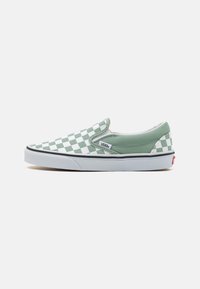 Gröna och vita rutiga slip-on Vans-skor med ovandel i canvas, rund tå, vit gummisula och diskret logotypdetalj på sidan.