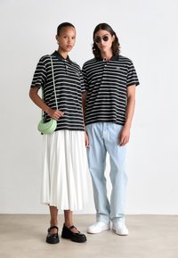 Tricouri polo cu dungi alb-negru, o fustă plisată albă, blugi de un albastru deschis și o geantă verde mentă. Pantofi cu toc gros negri și adidași albi.