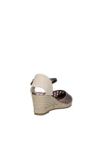 Sandalia de cuña en material trenzado marrón y crema, con un tacón texturizado y correa en el tobillo, con un diseño de espalda cerrada y punta abierta.
