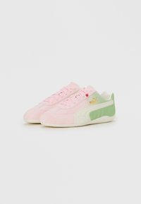Een paar roze en groene Puma-sneakers met witte zolen en een gouden logo op een witte achtergrond, gericht naar de linkerzijde.