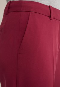 Burgundy skräddarsydda byxor med en slät yta, med flat front, bakficka och bältesöglor. Fint sydda detaljer synliga.