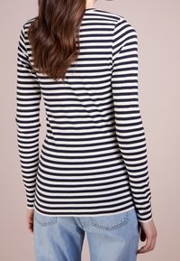 Långärmad skjorta med marinblå och vita ränder, tillverkad av mjukt tyg, med en figursydd design och rund halsringning. Ihop med ljusblå jeans.