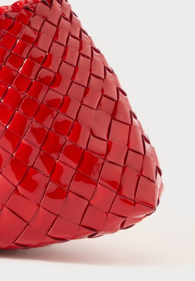 Κόκκινη πλεγμένη τσάντα με γυαλιστερή επιφάνεια, που έχει στρογγυλό σχήμα και περίπλοκη υφή με τετράγωνο σχέδιο. Δεν υπάρχουν ορατά μηχανικά μέρη.