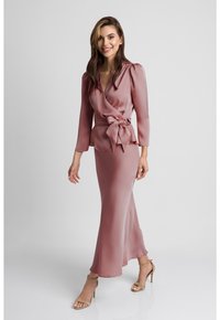 Długa, dopasowana sukienka z miękkiego różowego materiału z fasonem kopertowym, z paskiem w talii i długimi rękawami. Gładka tekstura i subtelny połysk.