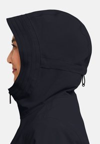 Giacca con cappuccio blu navy con colletto alto, caratterizzata da una texture morbida, coulisse regolabile e molteplici dettagli cuciti lungo il cappuccio.