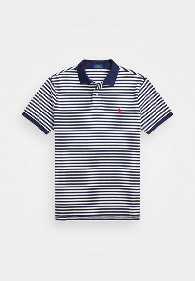 Jūras spēku un baltās svītrās polo krekls ar vienkāršu jūras zila apkakli. Iekļauj nelielu sarkanu logotipu uz krūtīm un īsām piedurknēm ar svītrām.