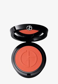 Fard à joues compact avec une teinte corail lisse et texturée à l'intérieur. Il présente un boîtier noir élégant avec une ouverture circulaire et un détail de logo en relief.