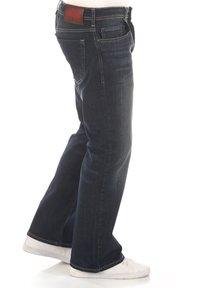 Jean en denim foncé à coupe droite, avec une étiquette en cuir sur la ceinture arrière, cinq poches et des accents de surpiqûres blanches.