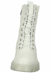 Botas de cuero blanco con cordones, puntera reforzada, textura suave y suela de goma gruesa y translúcida. Presenta herrajes de metal y cordones planos.