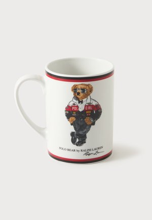 Tasse en céramique blanche avec un ours portant des lunettes de soleil, un pantalon noir et une veste rouge et blanche, étiquetée Polo Bear par Ralph Lauren.