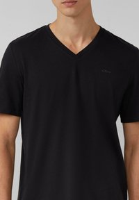 Czarny bawełniany T-shirt z dekoltem w serek, krótkimi rękawami i subtelnie umieszczonym logo na piersi, charakteryzujący się gładką, miękką teksturą.