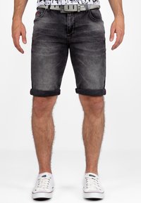 Zwarte denimshorts met omgeslagen zomen, grijze stiksels en een zilveren riem. Draag met witte canvas sneakers, wat een casual stijl toont.