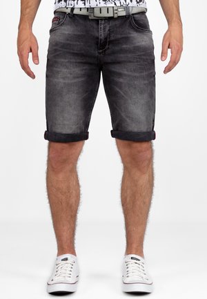 Shorts en denim noir avec ourlets retroussés, couture grise et une ceinture argentée. Portés avec des baskets blanches en toile, affichant un style décontracté.