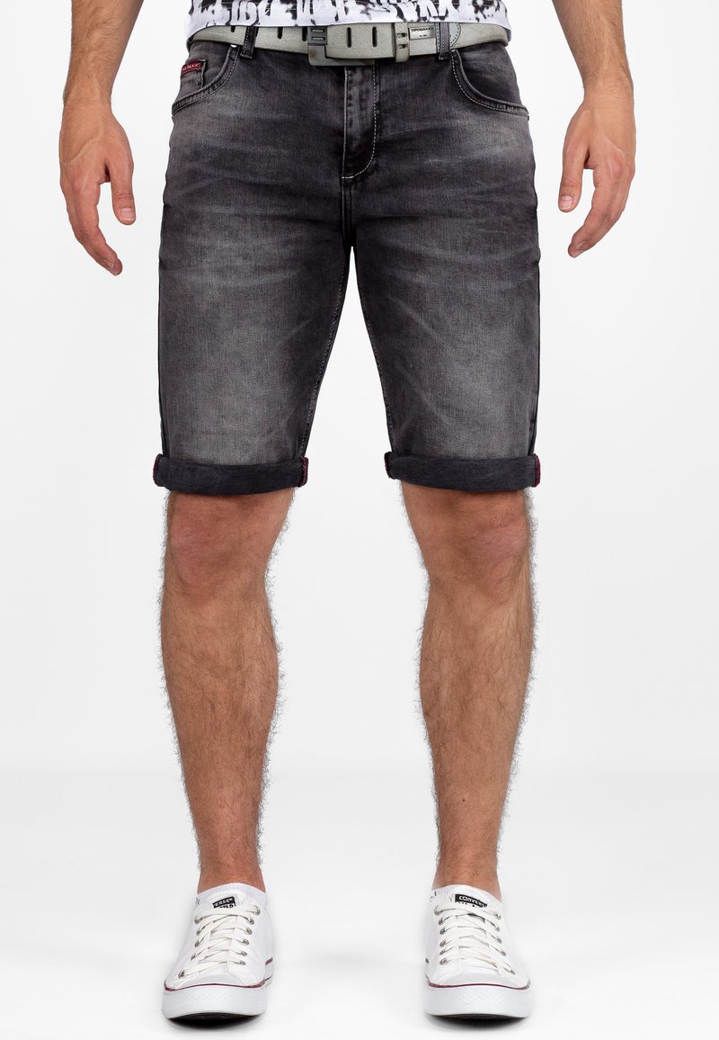 Zwarte denimshorts met omgeslagen zomen, grijze stiksels en een zilveren riem. Draag met witte canvas sneakers, wat een casual stijl toont.