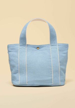 Hellblauer Canvas-Shopper mit zwei breiten Griffen und einem einzigen Druckknopfverschluss auf beigem Hintergrund.