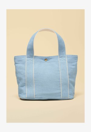 Hellblauer Canvas-Shopper mit zwei breiten Griffen und einem einzigen Druckknopfverschluss auf beigem Hintergrund.
