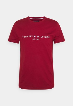 Rød T-shirt med korte ærmer med "Tommy Hilfiger" logo og teksten "EST. 1985" centreret på brystet.
