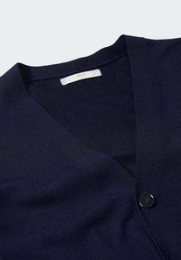 Cardigan bleu marine en tissu maille, avec un col en V et un seul bouton noir. Texture douce et design simple.