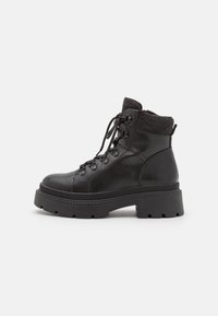 Bottines noires avec une tige texturée, bout rond et semelle épaisse. Dotées d'un laçage à l'avant et d'un col en tricot pour un confort supplémentaire.