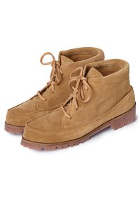 Botines de ante en marrón claro con puntera redondeada, suela plana de goma y diseño de cordones. Presentan una textura suave y un mínimo de costuras.