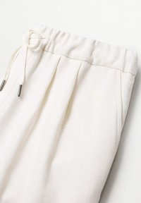 Białe spodnie lounge z teksturowanej tkaniny, elastycznym paskiem w talii, regulowanym sznurkiem do wiązania oraz plisami z przodu dla dodatkowego akcentu.