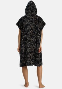 Poncho con capucha en tejido de toalla negro con un patrón floral en beis y rosa claro. Mangas cortas y aberturas laterales para mayor libertad de movimiento.