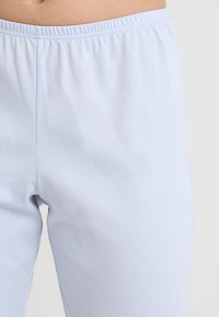 Světle modré bavlněné legíny s elastickým pasem, hladkou texturou a jednoduchým designem, které těsně přiléhají kolem pasu a nohou.