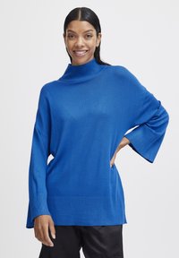 Pulover oversized bleu, cu un guler înalt cu dungi, mâneci largi și tiv cu dungi, fabricat dintr-un material tricotat moale. Textură netedă.