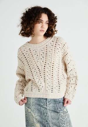 Knit cream sweater with open weave pattern, wide neckline, and long sleeves, paired with a textured snake print skirt in gray tones.