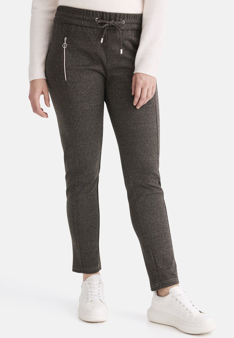 Dunkelgraue Sweatpants aus strukturiertem Stoff, mit elastischem Bund, Kordelzugverschluss und einer Reißverschlusstasche. Kombiniert mit weißen Sneakers.