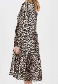 Klänning med leopardmönster, långa ärmar, volangskikt och en flödande silhuett. Tillverkad av lätt tyg för komfort.