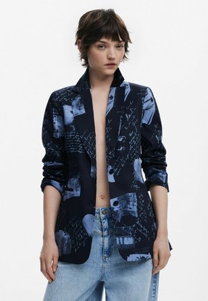 Navyblazer mit einem Collage aus blauen Grafikdrucken und handgeschriebenem Text, mit hochgerollten Ärmeln und einer taillierten Passform.