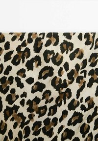 Taches irrégulières marron et noires d'imprimé léopard sur fond beige ressemblant à un motif de fourrure animale.