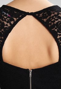 Abito in pizzo nero che mette in risalto un motivo floreale, design con schiena aperta e chiusura con zip. Tessuto morbido, con un'apertura a forma di chiave sul collo.