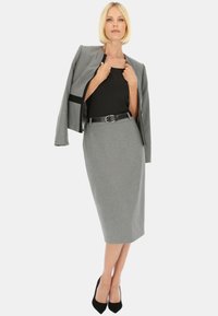 Szary marynarka w stylu tailored i spódnica ołówkowa, z czarnym paskiem. Tkanina ma gładką teksturę z subtelnymi wzorami. Czarne szpilki.