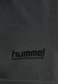 Zwarte sportstof met een gestructureerd patroon en een opvallend zwart "hummel PERFORMANCE" logo. Helle textuur met een lichte glans.