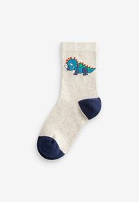 Calzini lavorati a maglia di colore crema con un design di dinosauro blu, con accenti in blu navy sulla punta e sul tallone. Texture liscia con bordo a coste.