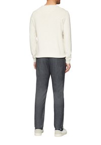 Crème sweatshirt met ronde hals en geribde manchetten, gecombineerd met donkere textuurbroeken en witte sneakers, gezien vanuit de achterkant.