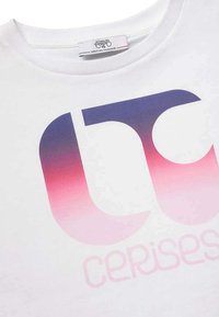 T-shirt en coton blanc avec un grand logo dégradé en violet et rose, avec le mot "cerises" en rose clair en dessous du logo.