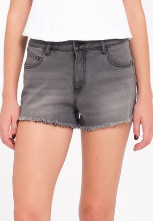 Femme portant un short en jean gris taille haute avec ourlet effiloché et poches avant, associé à un haut blanc rentré.